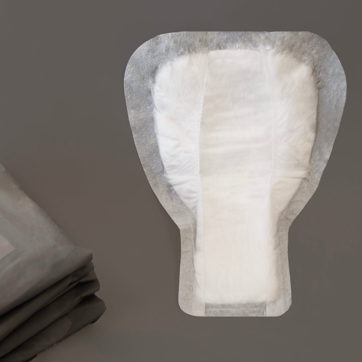 Photograph of a W/O men's stress incontinence shield showing the shield's shape and that it is white in colour.