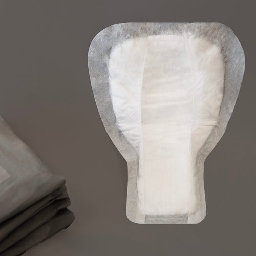 Photograph of a W/O men's stress incontinence shield showing the shield's shape and that it is white in colour.