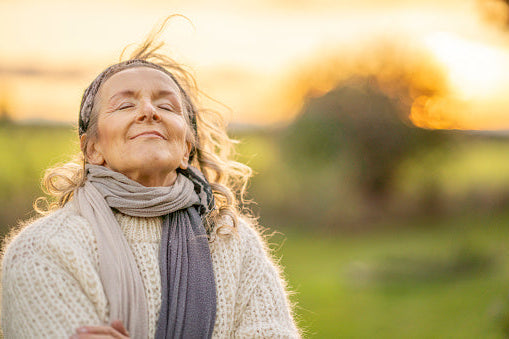 Woman with closed eyes standing outdoors in a natural setting