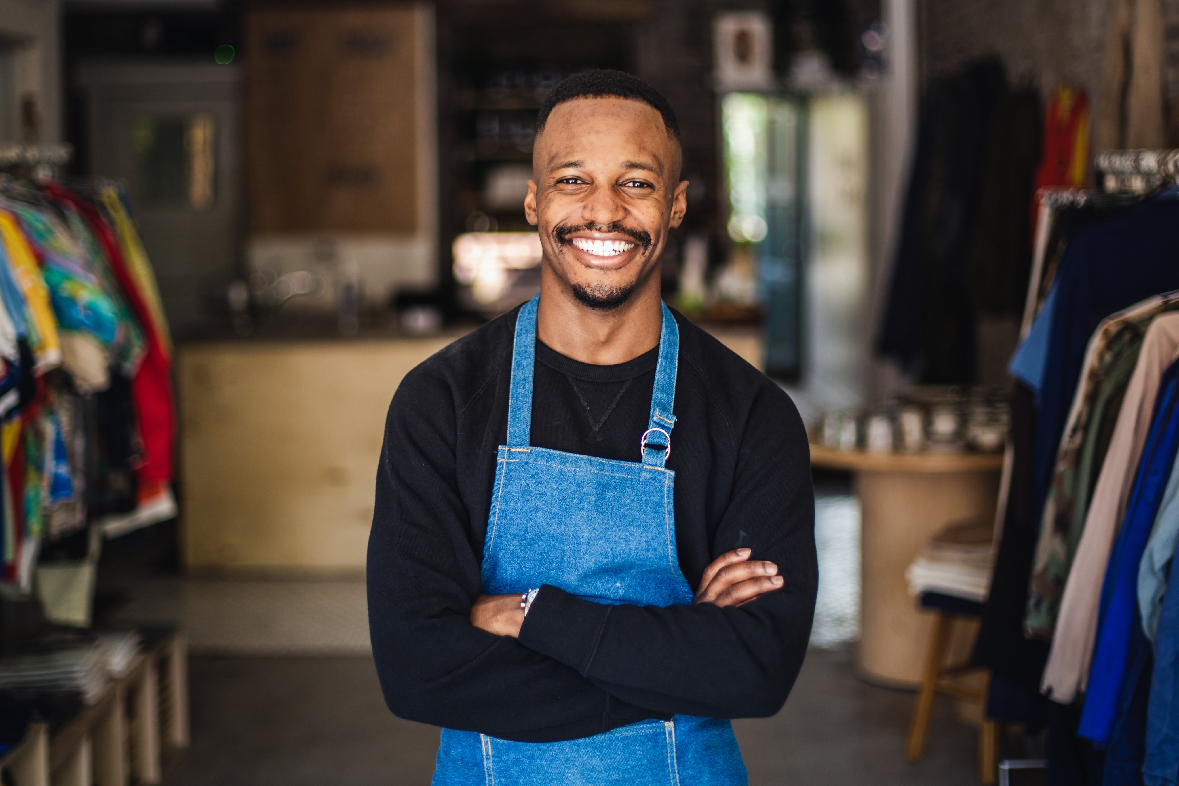 Man smiling wearing an apron and standing in a shop